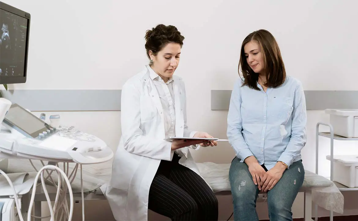 doctor patient sitting on bed in room with tablet and healthcare machine